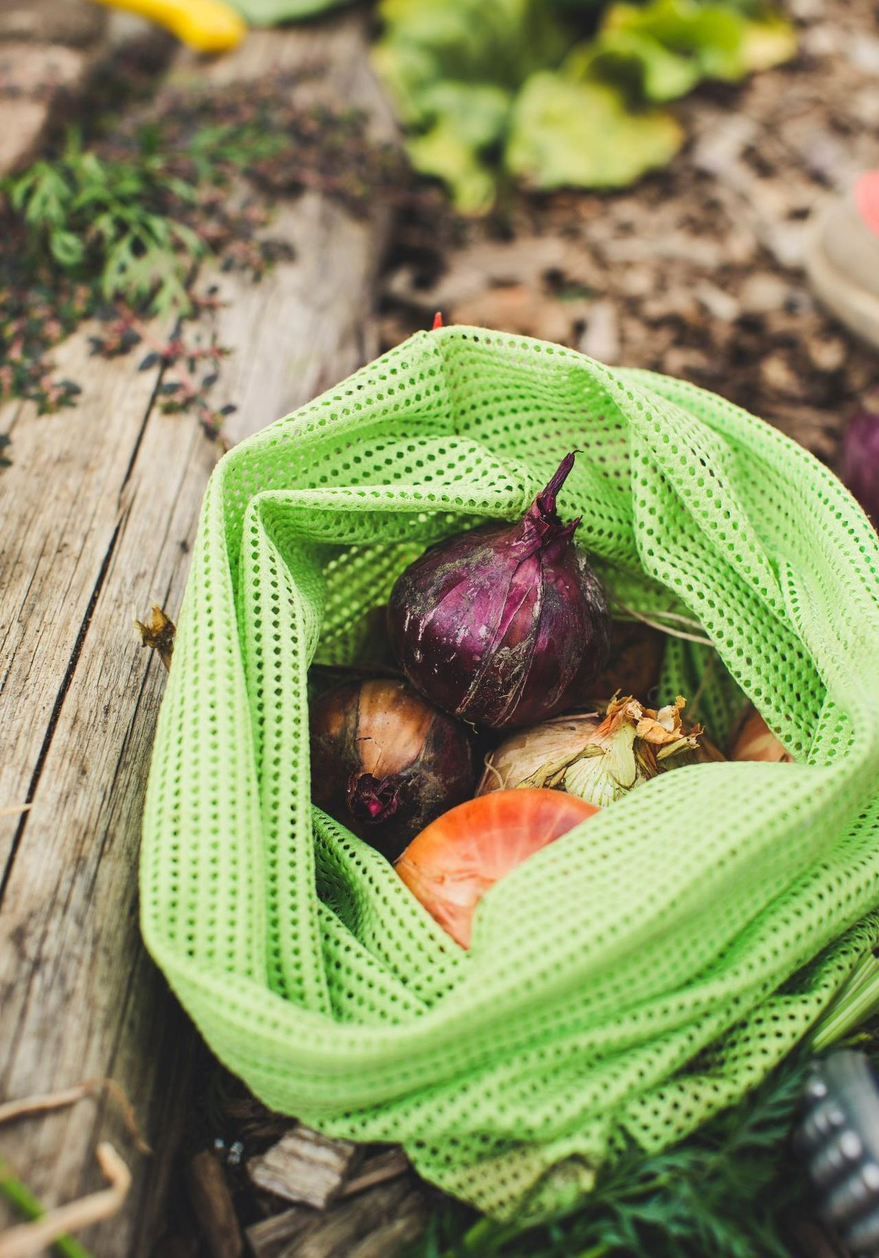 a green mesh bag filled with vegetables on top of a wooden table